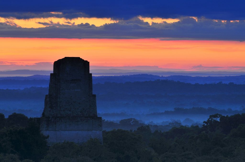 A striking view of the pyramid of Tikal and the city beneath the rainforest. Shutterstock.