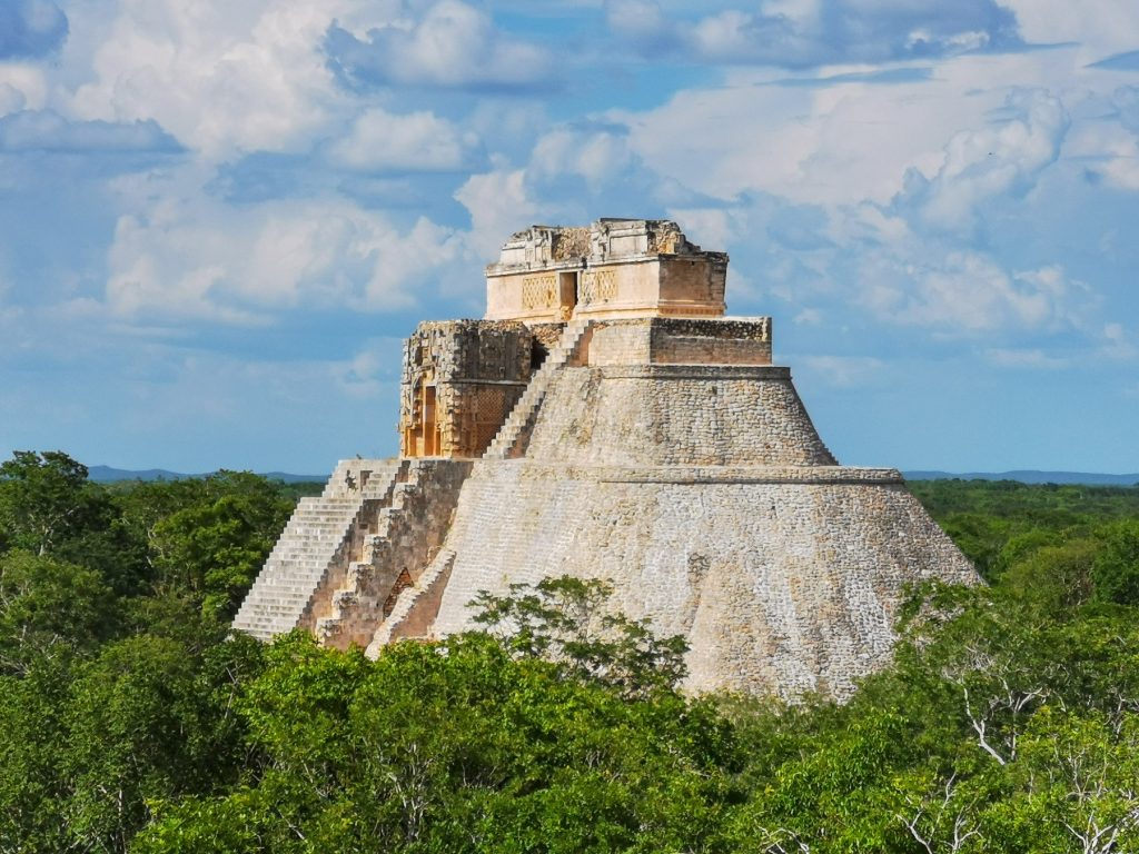 A view of the pyramid of the magician at Uxmal protruding from the forest. This pyramid is the tallest structure at Uxmal. Shutterstock.